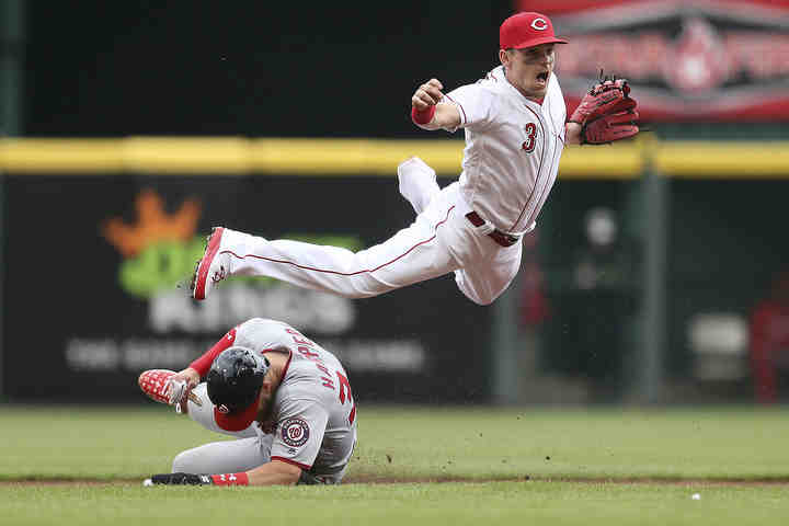 Washington Nationals right fielder Bryce Harper (34) slides to break up a double play as Cincinnati Reds second baseman Scooter Gennett (3) throws to first base in the first inning of the Opening Day game at Great American Ball Park in Cincinnati.     (Kareem Elgazzar / The Cincinnati Enquirer)
